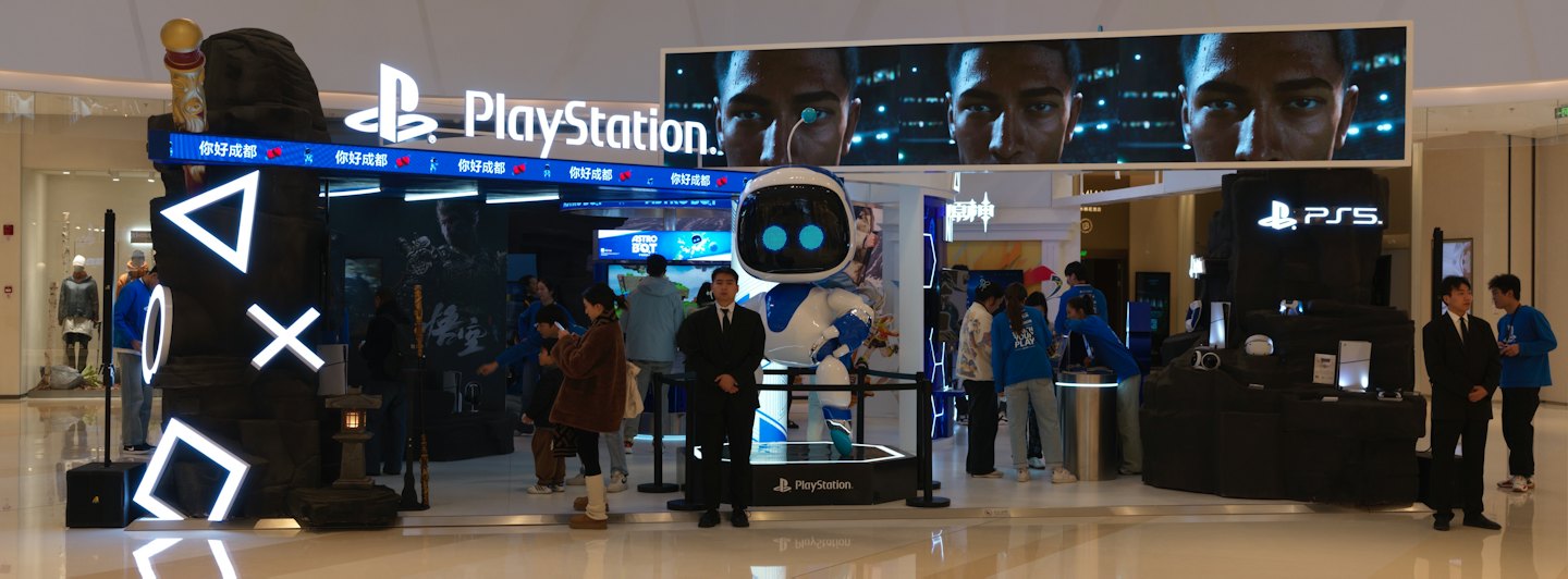 Crowd gathers at a PlayStation booth in a shopping mall.