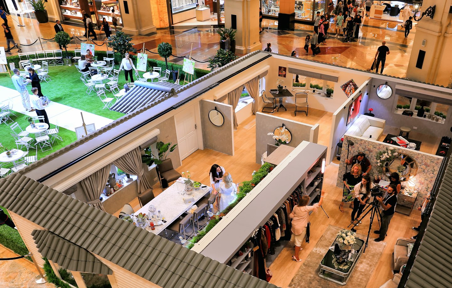 People participate in interactive displays throughout a busy shopping mall.