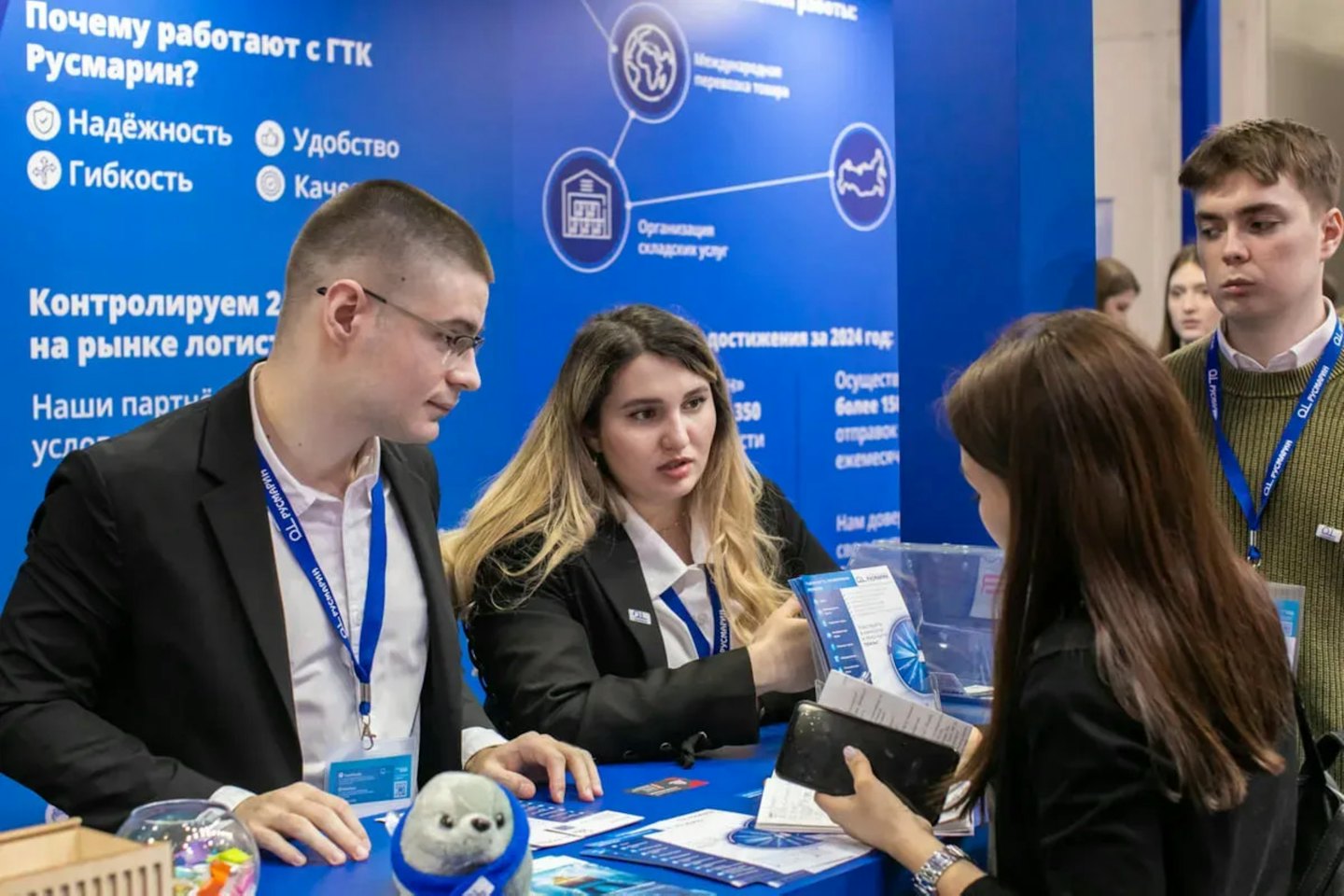 Professionals discuss logistics services at a blue exhibition booth.