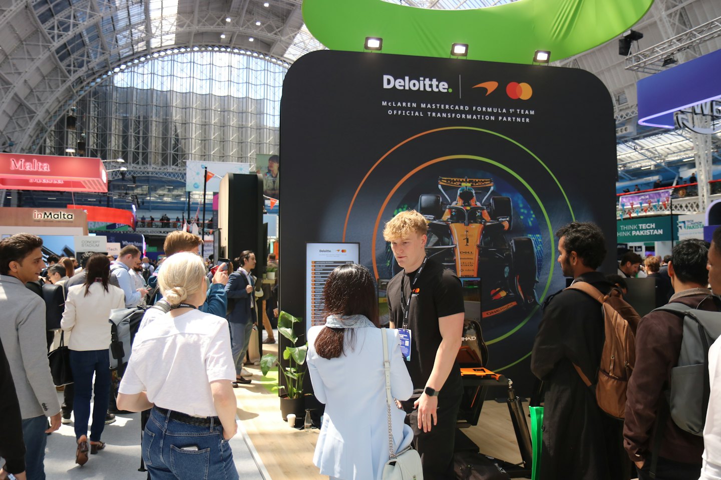 Business professionals network at a trade show booth with branding.