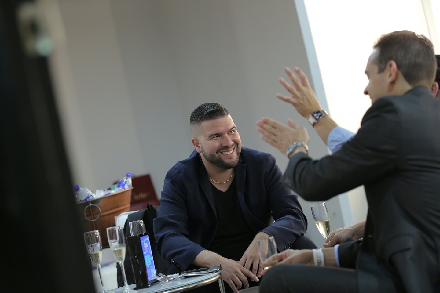 Two men in business attire talking at an indoor event.